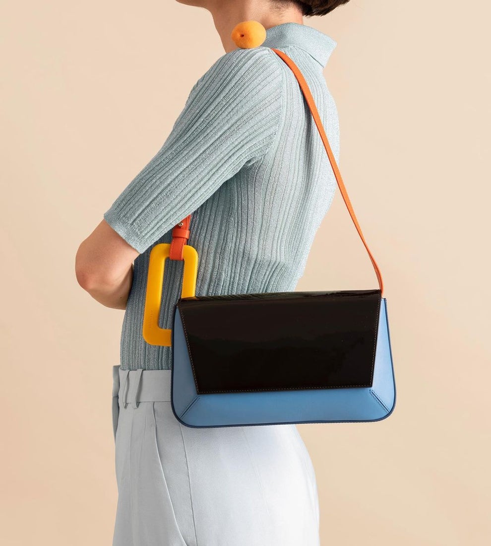 A woman models a black and blue shoulder bag. 