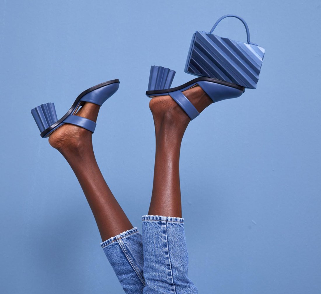 A woman's feet in the air, balancing a blue bag. 